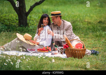 Giovane al picnic sollevando il vetro con vino spumante Foto Stock