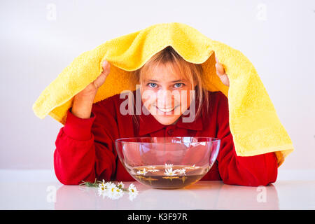 Donna mentre inalazione su un bagno di vapore vicino fiori di camomilla Foto Stock