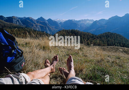 Gambe su un prato davanti al panorama di montagna Foto Stock