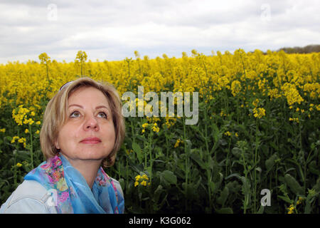 Giovane donna bionda in un campo di colza Foto Stock