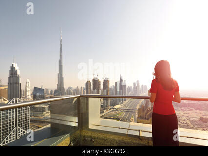Donna asiatica che si affaccia sul panorama urbano di Dubai Foto Stock