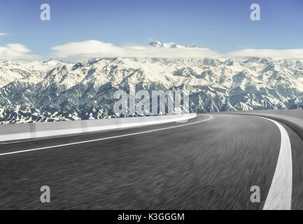 Strada asfaltata con montagne innevate sullo sfondo Foto Stock