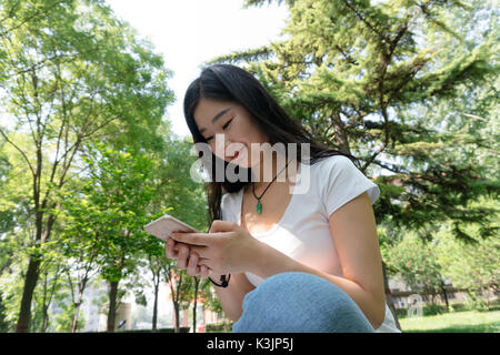 Closeup ragazza utilizzare un telefono cellulare nel parco Foto Stock