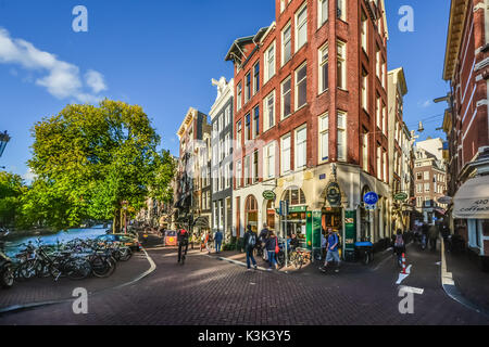 Una stretta edificio che ospita un negozio su un incrocio con una stretta strada che costeggia un canale ad Amsterdam in una giornata di sole in inizio di caduta Foto Stock