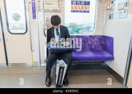 Giappone, Hoshu, Tokyo, treno passeggeri con computer e iPhone Foto Stock