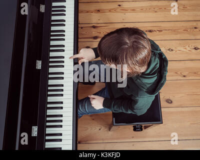 Ritratto di un ragazzo giocando su un nero pianoforte digitale - elevato angolo di visione Foto Stock