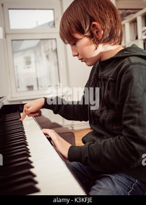 Ritratto di un ragazzo giocando su un nero pianoforte digitale Foto Stock