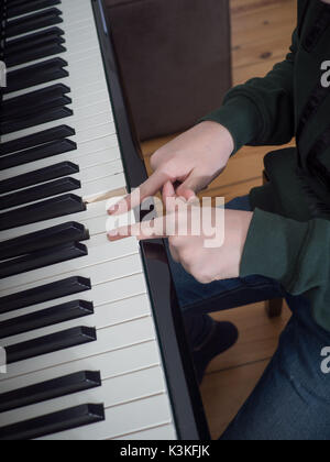 Chiudere fino alle mani di un bambino sui tasti di un pianoforte nero Foto Stock