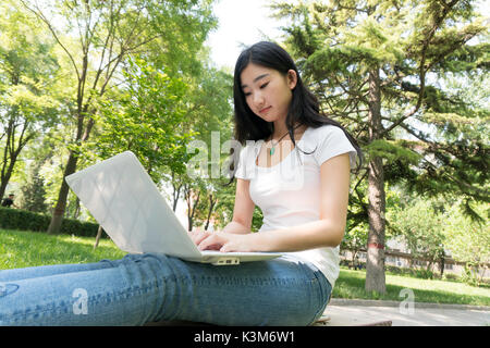 Bella asiatica studente di college con il computer portatile all'aperto Foto Stock