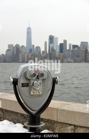 Binocoli a gettoni puntati verso lo skyline di New York da Ellis Island. Foto Stock