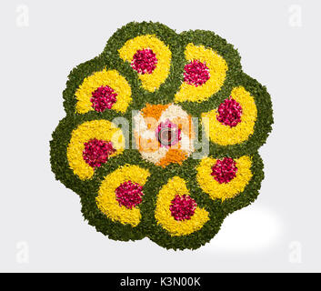 Flower rangoli di Diwali o pongal o onam realizzati utilizzando calendula o zendu fiori rosso e petali di rosa su sfondo bianco con diwali diya Foto Stock