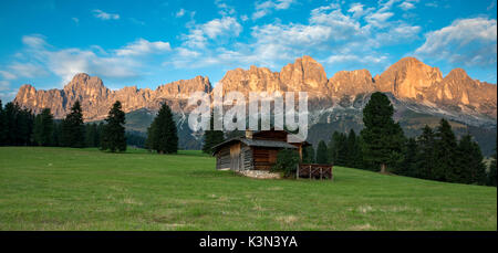 Carezza, Dolomiti, Alto Adige, Italia. Rifugio di montagna nei pascoli di Colbleggio. Sullo sfondo le cime del gruppo del Catinaccio / Rosengarten Foto Stock