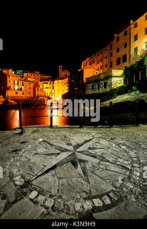 Tellaro di notte con la rosa dei venti impresso sul piccolo molo del villaggio, Liguria, Italia Foto Stock