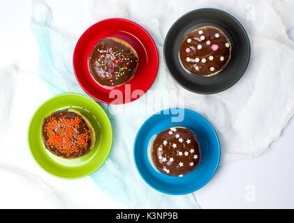 Decorate le ciambelle su piastre colorate vista superiore Foto Stock