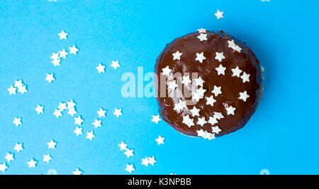 Stella decorata a forma di ciambella di cioccolato su sfondo blu Foto Stock