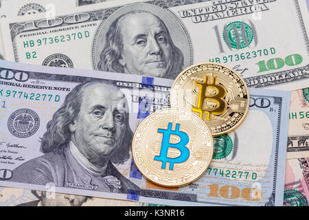 Primo piano di oro giallo e blu bitcoin su un centinaio di dollaro Foto Stock