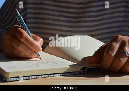 Studente di Dottorato di Ricerca iscritto elenco di obiettivi in un notebook / ufficiale Foto Stock