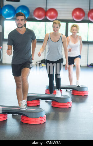 Lavoro di gruppo con pesi e stepper in palestra Foto Stock