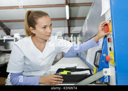 Femmina giovane farmacista utilizzando la macchina presso il laboratorio Foto Stock