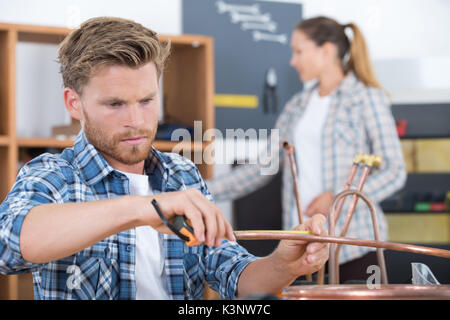 Plumber avvitando il dado del tubo con la chiave Foto Stock
