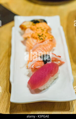 Premium Set Sushi includono Engawa, Hamachi Hotate, Toro, salmone serviti con Wasabi e parentesi di cipolla verde guarnire sulla pietra bianca piastra Foto Stock