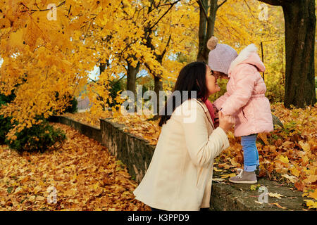 La madre cammina con un bambino nel parco in autunno. Foto Stock