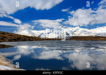 Il lago degli Andossi lago ghiacciato di fusione in tarda primavera, con Pizzo Quadro in background, Valle Spluga, provincia di Sondrio, Lombardia, Italia Foto Stock