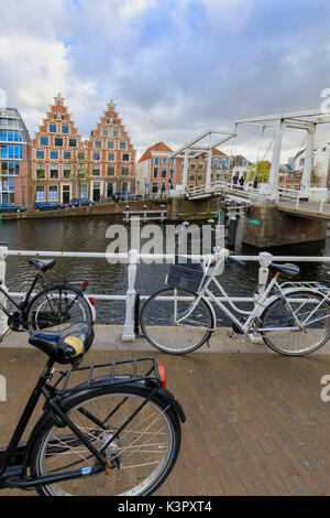 Le biciclette in banchina del canale del fiume Spaarne con tipiche case sullo sfondo Haarlem Olanda settentrionale dei Paesi Bassi in Europa Foto Stock