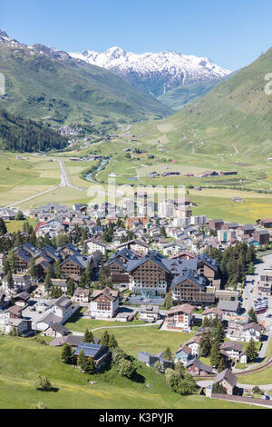 Il villaggio alpino di Andermatt circondato da prati verdi e cime innevate sullo sfondo del Cantone di Uri in Svizzera Europa Foto Stock