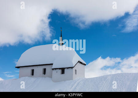 Cielo blu e nuvole frame la chiesa alpino immerso nella neve Bettmeralp distretto di Raron nel canton Vallese Svizzera Europa Foto Stock