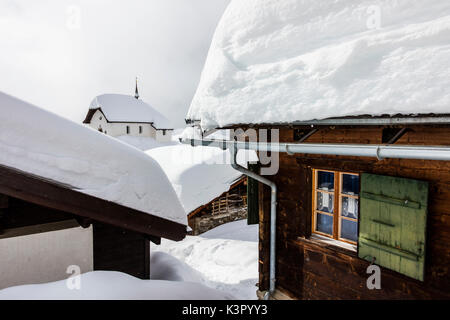 La chiesa alpina circondata da baite di montagna immerso nella neve Bettmeralp distretto di Raron nel canton Vallese Svizzera Europa Foto Stock