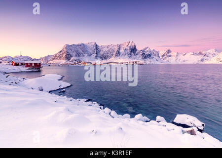 I colori dell'alba telai le case di pescatori circondato da mare frozen Reine Bay Nordland Isole Lofoten in Norvegia Europa Foto Stock