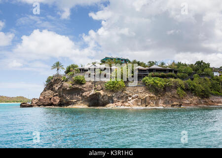 Il turchese del mare dei Caraibi e un villaggio turistico visto da un tour in barca Antigua e Barbuda Leeward Islands West Indies Foto Stock