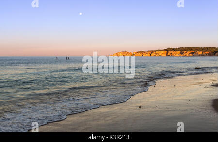 Il cielo rosa all'alba illumina l'oceano e scogliere a Praia do Vau Portimao distretto di Faro Algarve Portogallo Europa Foto Stock