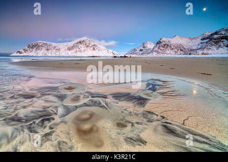 Luna piena riflessa sulla sabbia nel paesaggio surreale della spiaggia Skagsanden Flakstad Nordland county Isole Lofoten in Norvegia Europa Foto Stock