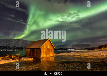 Northern Lights illumina la cabina in legno a Lenangsoyra Alpi Lyngen Tromsø Lapponia Norvegia Europa Foto Stock