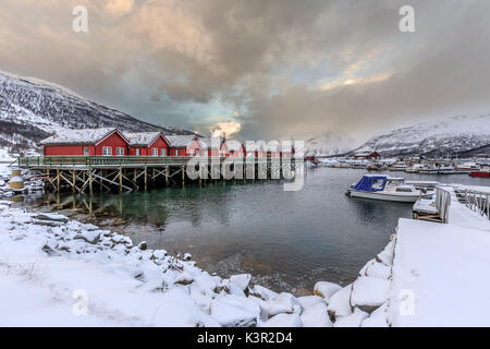 Rosso tipiche baite in legno dei pescatori in presenza di neve e ghiaccio paesaggio delle Alpi Lyngen Tromsø Lapponia Norvegia Europa Foto Stock