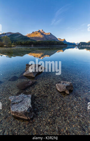 Alba illumina i picchi si riflette nelle calme acque del lago di Sils Engadina Canton Grigioni Svizzera Europa Foto Stock