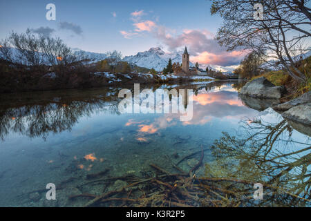 Alba illumina le vette innevate e la torre campanaria si riflette nel lago di Sils Engadina Canton Grigioni Svizzera Europa Foto Stock