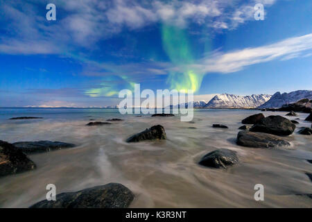 Northern Lights illuminano il paesaggio intorno Gymsøyand e le cime innevate. Isole Lofoten Norvegia del Nord Europa Foto Stock