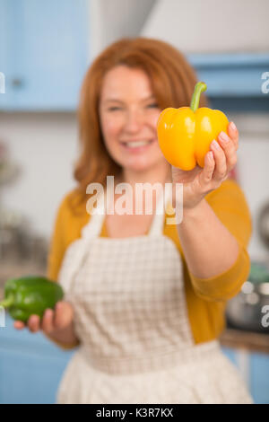 Vista ravvicinata di peperone giallo in mano di attraente casalinga. Foto Stock