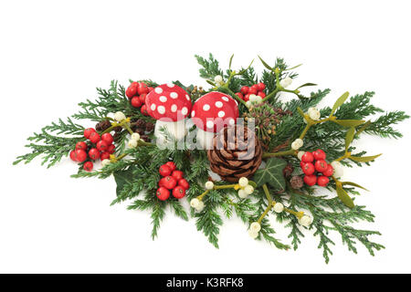 Fantasy decorazione di Natale con fly agaric ornamenti a fungo, agrifoglio, edera, vischio, edera, ginepro e cedro cipresso foglie e rametti di pigna su wh Foto Stock