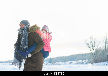 Padre dona piggyback ride per la figlia in inverno e divertirsi Foto Stock