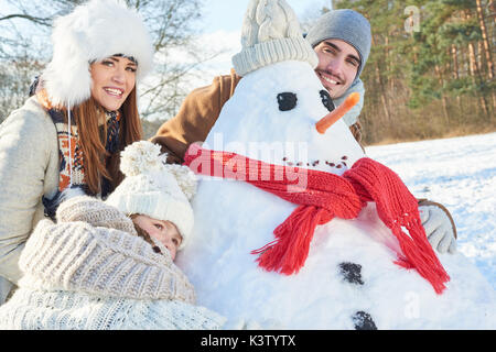 La famiglia felice di giocare e la costruzione di pupazzo di neve insieme Foto Stock