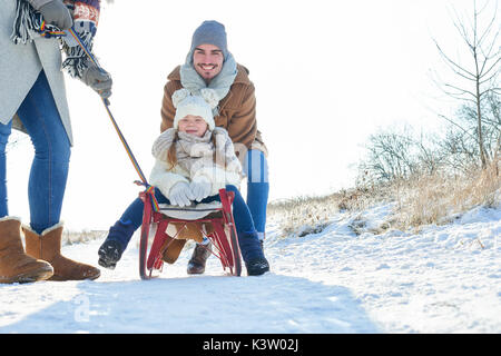 Famiglia con bambino su sled divertimento in inverno Foto Stock