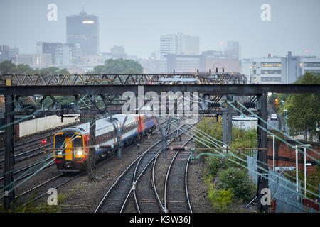 East Midlands classe treni 158 diesel multiple unità della linea ferroviaria da Ardwick che conduce alla stazione ferroviaria Manchester Piccadilly Station con skyline della città costa ovest Foto Stock