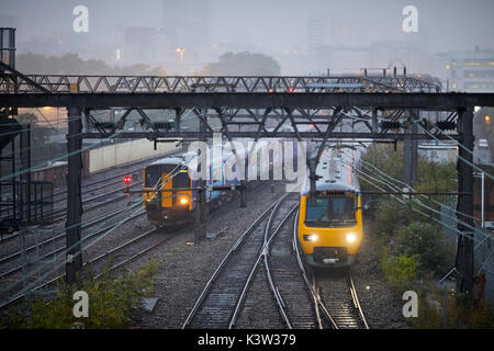 Classe settentrionale 156 e 323 unità multiple linea ferroviaria da Ardwick che conduce alla stazione ferroviaria Manchester Piccadilly Station con skyline della città Linea principale della costa occidentale Foto Stock