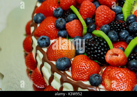 Torta di velluto con belle bacche fragole, lamponi mirtilli e menta giacente sulla carta argentata Foto Stock