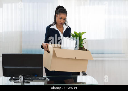 Triste imprenditrice africana portando scatola con i suoi averi in Office Foto Stock