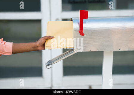 Close-up di persona mettendo mano lettere nella casella di posta Foto Stock